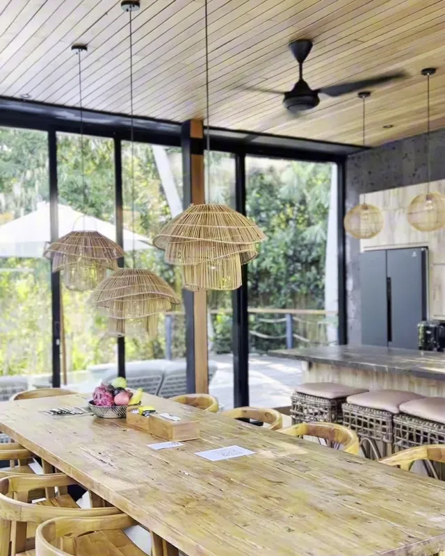 The dining room, long wooden table set under the jungle